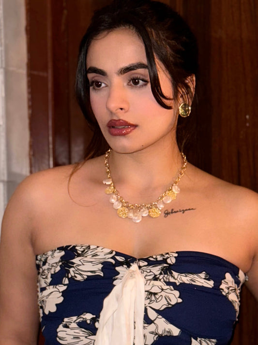 wearing a strapless floral dress with gold jewelry indoors.