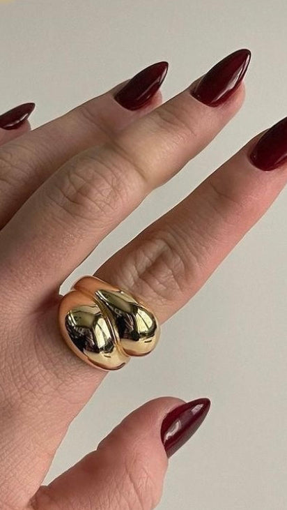 Hand wearing two gold rings with a plain background